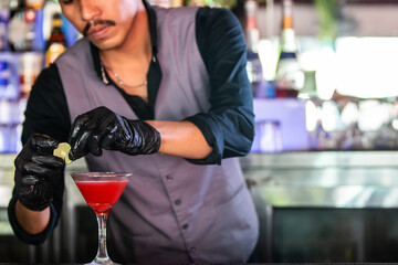 Close up of expert barman with mustache making cocktail at night club or bar