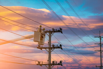 electrician works on bucket car to maintain high voltage transmission lines.