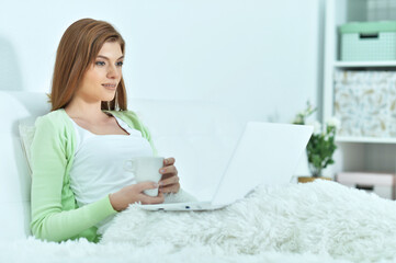 Young woman using laptop in bed at home