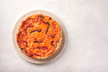 Homemade quiche pie with chicken, dried tomatoes, cheddar cheese on light background. Top view, copy space