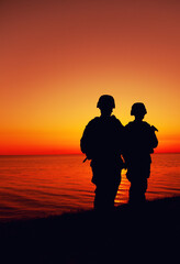 Silhouette of two Marines soldiers, special operations infantrymen or coast guard fighters in...