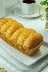 Roti Sobek or pull out Soft bread on ceramic white plate, tea time concept with a cup of tea....