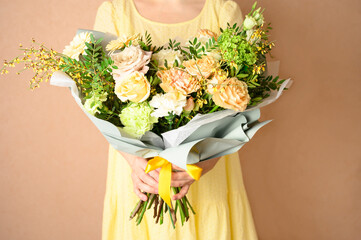 Woman holding a beautiful bouquet with flowers on beige background. Front view. Valentine's, women's, mother's day. Spring, summer concept
