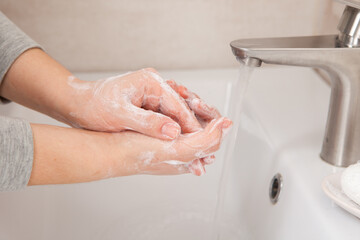 Proper hand washing as a prevention of coronavirus. Close-up of women's hands in soap in the bathroom