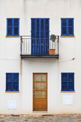 traditional spanish white house facade with blue shutters on door and windows