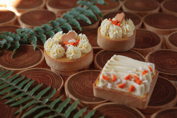 dessert, cheesecake with mango and passion fruit in the form of brownies with mousse on top. Decorated with cookies in the form of a heart. On a wooden table in a white plate
