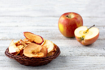 Naklejka na ściany i meble A pile of dried slices of apples and fresh ripe apples on wooden background.