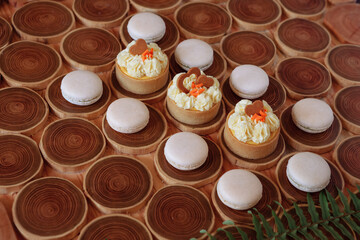 white delicate lowly macaroons on a wooden background. The pastel tone of the cream inside the French cookies