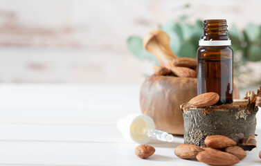 Banner, organic cosmetics concept, glass bottle with oil, pipette and almonds on light wooden background