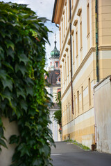 Small alley with a view of the church tower in Litoměřice Leitmeritz in the Czech Republic, with leaves on a wall