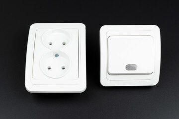 close-up of electrical outlet and light switch on black background