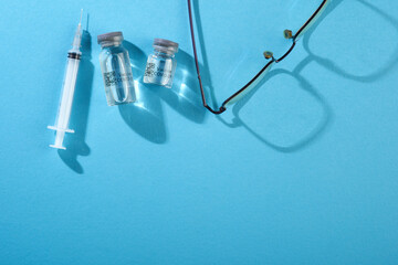 bottle of covid19 vaccine and syringe isoltaed blue background