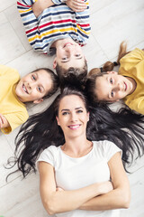Mother, twin girls and a boy lie on the floor looking up, smiling