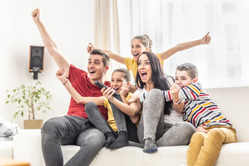 Fototapeta Enthusiastic family of five cheers at home watching sports on TV obraz