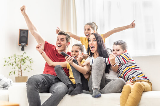 Enthusiastic family of five cheers at home watching sports on TV