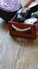 a decorative box with farm vegetables located on a wooden brown textured table top with empty space for text, vertical image orientation of an organic vegetable harvest with copy space