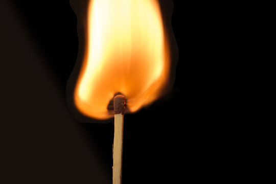 Lone burning match with the flame in the upper left side of the frame isolated on black background 