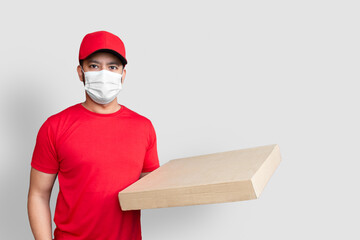 Fototapeta na wymiar Delivery man employee in red cap blank t-shirt uniform face mask hold empty cardboard box isolated on white background