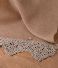 tablecloth with crochet and pearls photographed on a paper background