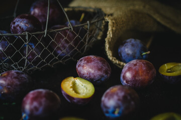 plums on black wooden table with metal basket