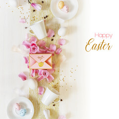 Easter holiday romantic morning still life with cups of coffee, eggs, a gift box and rose petals on white wooden background with greeting text. Easter celebration, spring impression. Greeting card