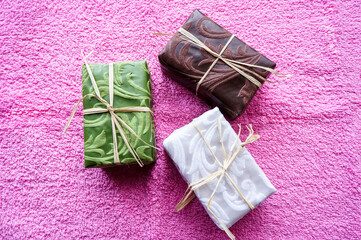 Three pieces of soap in a colorful package on a towel. Top view
