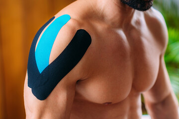 Kinesiology therapeutic tape. Patient with elastic adhesive tape on a shoulder. - obrazy, fototapety, plakaty