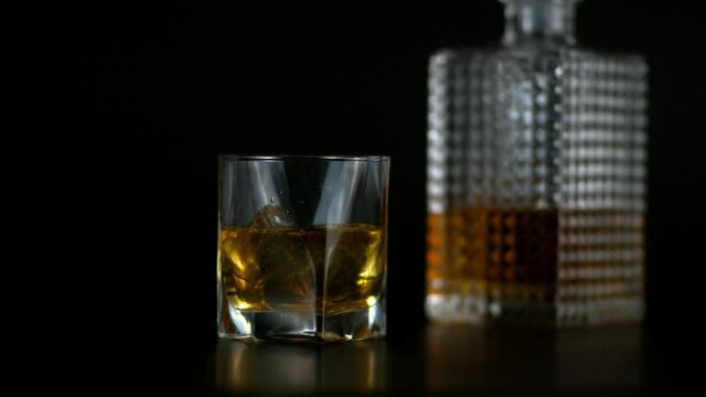 Close up Shot of Whiskey in Transparent Glass and Bottle with Black Background 