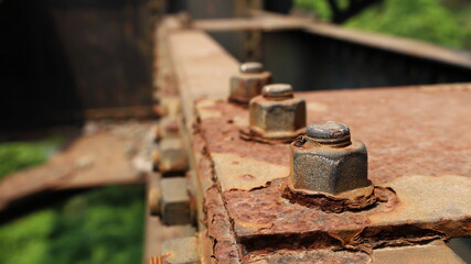 Rusted bolts and threads on the old bridge structure. On a green tree background. Close focus and select objects