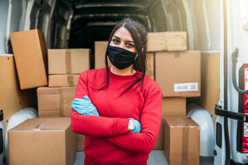 Portrait of young woman shipper with her van during the delivery round in global pandemic from...
