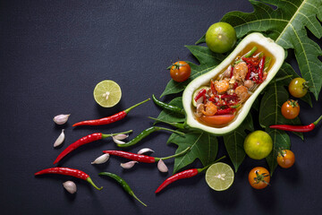 Papaya salad, Thai food cooked with papaya, tomato, green beans and peanuts Placed on a black table.