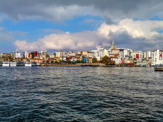 Istanbul, Turkey - October 29, 2019: View from the sea to the Karakoy district with Galata Tower against the backdrop of a cloudy sky in Istanbul. City skyline with old colorful buildings on the shore