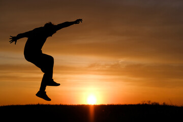 Man silhouette jump at sunset background at summer.