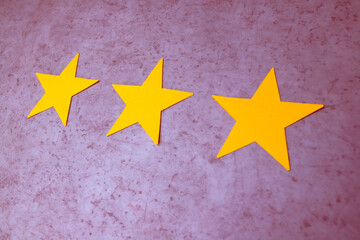 Three yellow stars on purple concrete background. Negative feedback.