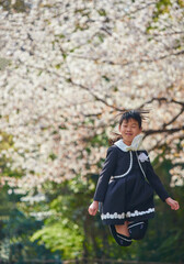 桜満開の公園で遊んでいる小学生の一年生の子供の様子