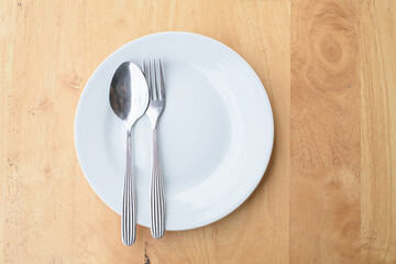 Empty plate and spoon fork on table.