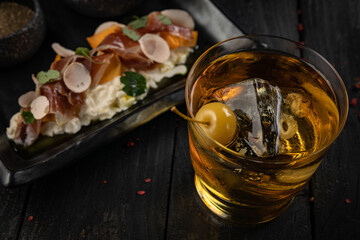 Cocktail with ice and cherry on a dark table. Snacks for a cocktail
