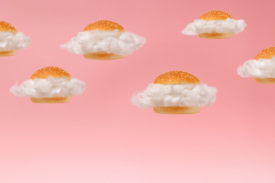 White clouds inside burger buns floating against pink sky background. Surreal fast food hamburger group concept. 2021 minimal abstract summer healthy low calorie diet food idea.