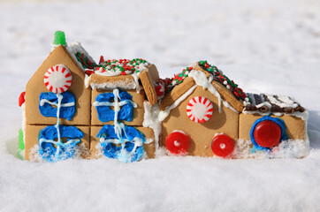 cute little Christmas gingerbread house decorated with icing and candy sitting in snow