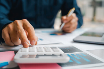 Male accountants or businessmen use a calculator and laptop to calculate investment results. And making financial reports on the desk Business finance accounting concept