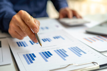 The hand of a male accountant or businessman examining the investment results. And making financial document reports on the desk Business finance accounting concept