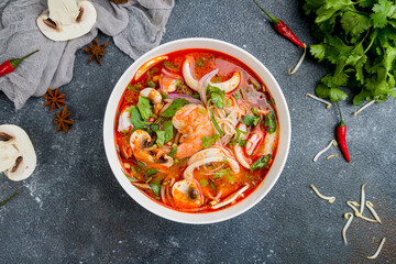 Tom Yam soup with shrimps and squids and rice on dark concrete table