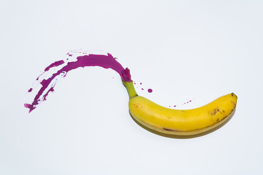 Organic yellow banana with purple paint on white background. Summer fruit minimal flat lay artistic concept.