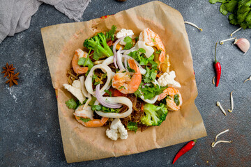 Vietnamese noodles Mi Sao with shrimps, vegetables and squids on dark stone table top view