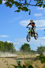 Plakat Motocross Rennen, Motorradfahrer springt mit Enduro durch die Luft bei blauem Himmel