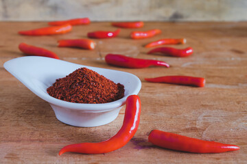 Chili powder and fresh peppers on old wood table background.