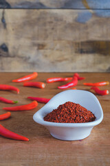 Chili powder and fresh peppers on old wood table background.