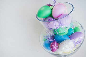 Glass vase filled with colorful Easter eggs 