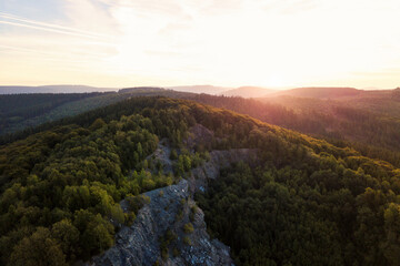 Aerial photograph of a beautiful, atmospheric sunrise over a mountain with forest. Drone shot from the Sauerland, Germany.