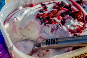 Vanilla ice cream with berries melts under the hot sun